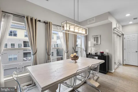 a view of a dining room and livingroom with furniture wooden floor a rug a flat screen tv a painting and a chandelier