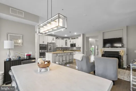 a kitchen with stainless steel appliances kitchen island granite countertop a sink a stove and a dining table with wooden floor