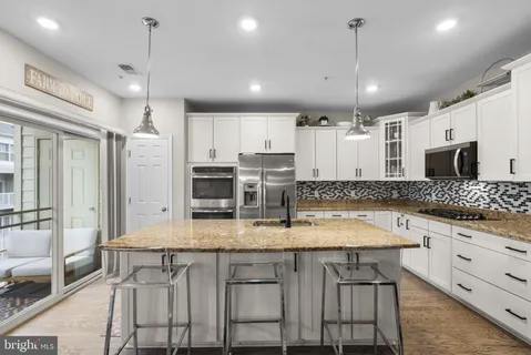 a large kitchen with granite countertop lots of counter space and stainless steel appliances