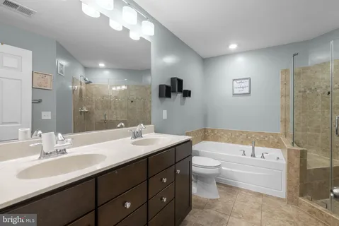 a bathroom with a double vanity sink toilet mirror and bathtub