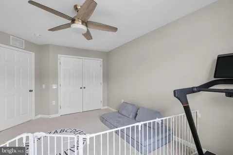 a view of a hallway to a bedroom with wooden floor and a ceiling fan