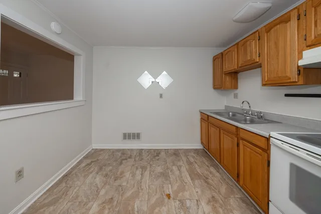 a kitchen with granite countertop a sink cabinets and wooden floor