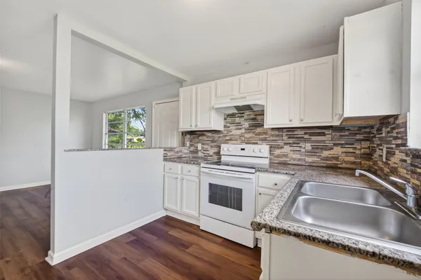 a kitchen with stainless steel appliances granite countertop a sink stove and white cabinets