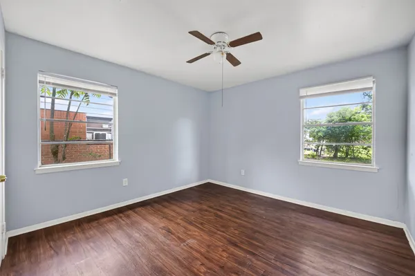 a view of a big room with wooden floor and windows