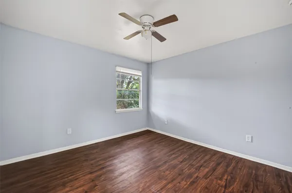 an empty room with wooden floor and ceiling fan