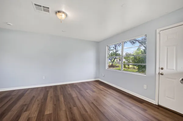 an empty room with wooden floor and windows