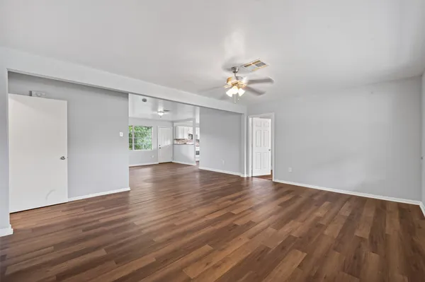 a view of an empty room with a window and wooden floor