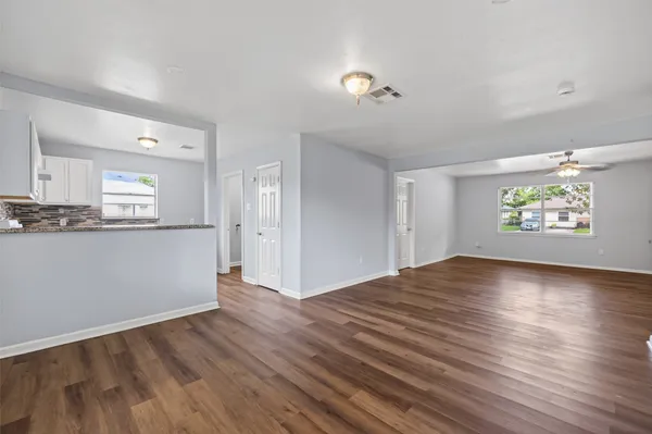 a view of an empty room with a window and wooden floor
