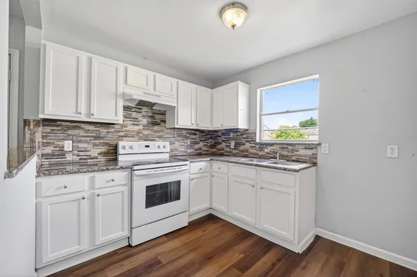 a kitchen with stainless steel appliances granite countertop a stove a sink and white cabinets