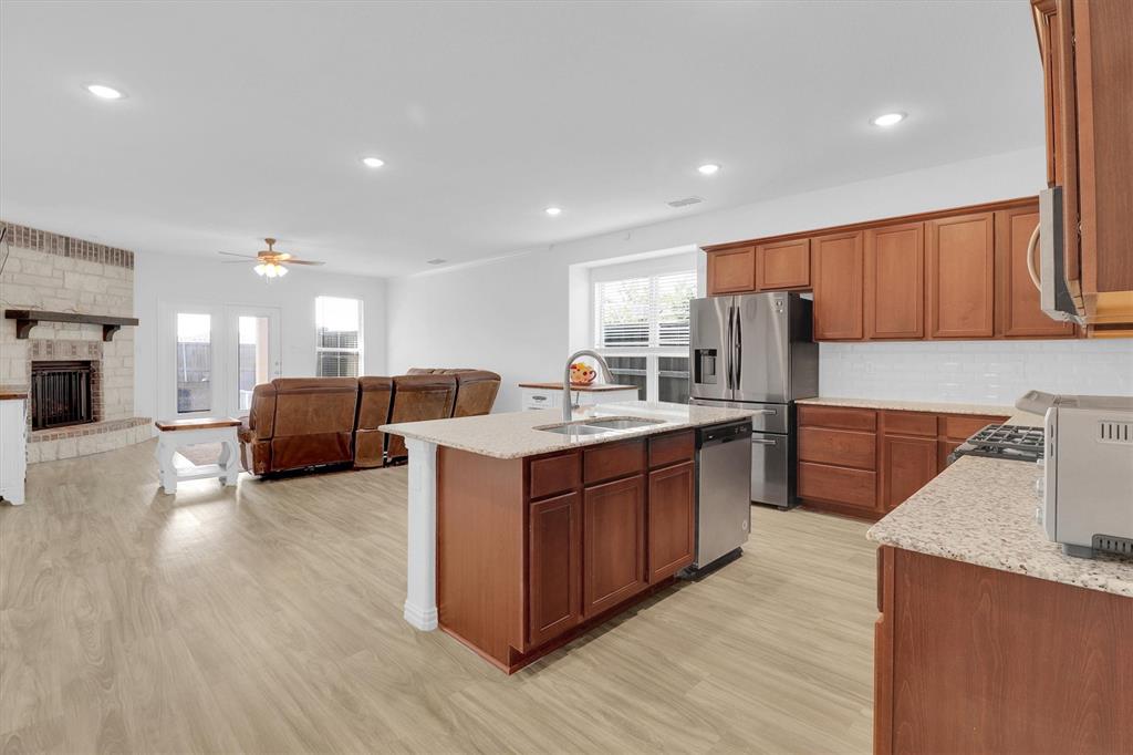 1446 Whitewater Drive Little Elm, TX 75068 - Photo 17 of 35 a kitchen with stainless steel appliances granite countertop a stove a sink dishwasher a refrigerator and a oven with wooden floor