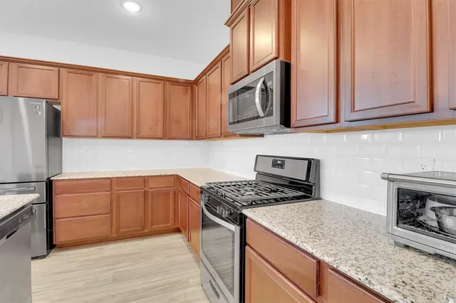 a kitchen with stainless steel appliances granite countertop a sink a stove and a refrigerator