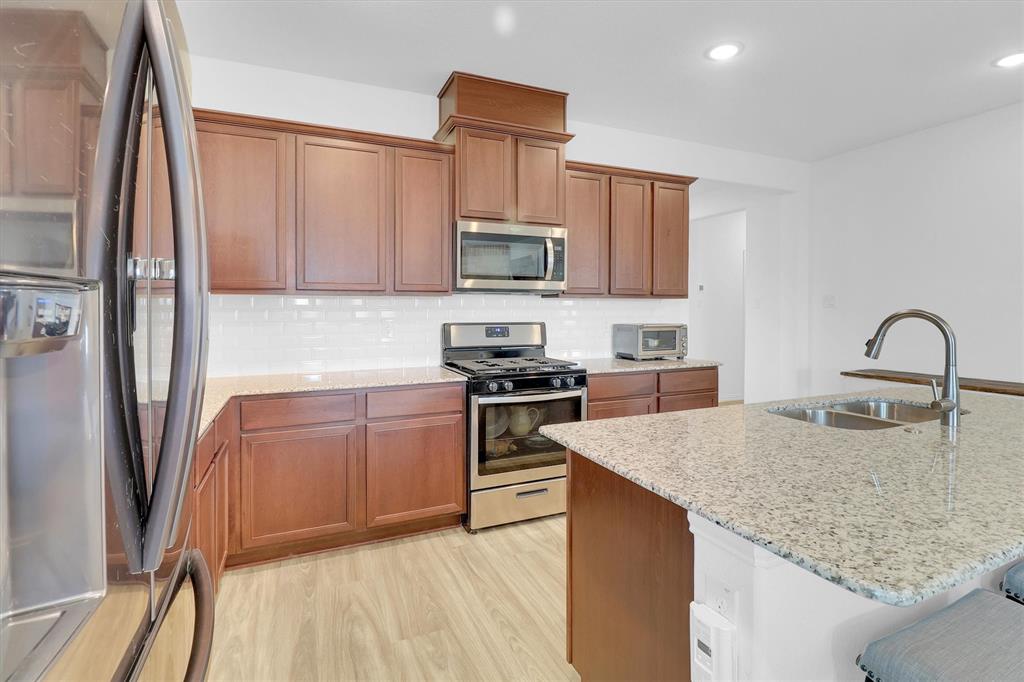 1446 Whitewater Drive Little Elm, TX 75068 - Photo 21 of 35 a kitchen with stainless steel appliances granite countertop a sink stove and refrigerator