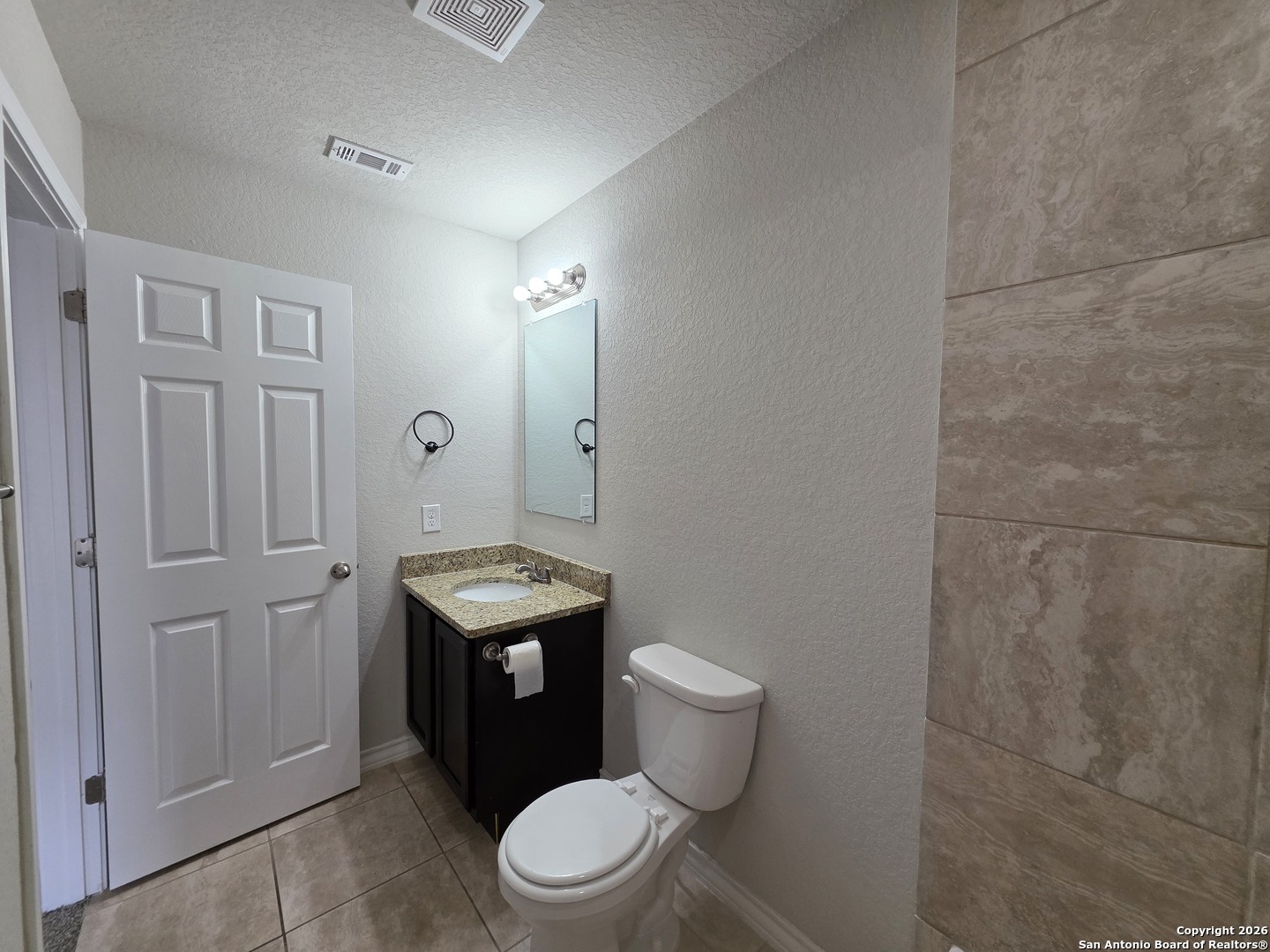 16909 Dancing Ava, Unit 2 Selma, TX 78154 - Photo 11 of 22 a bathroom with a granite countertop toilet a sink and a mirror