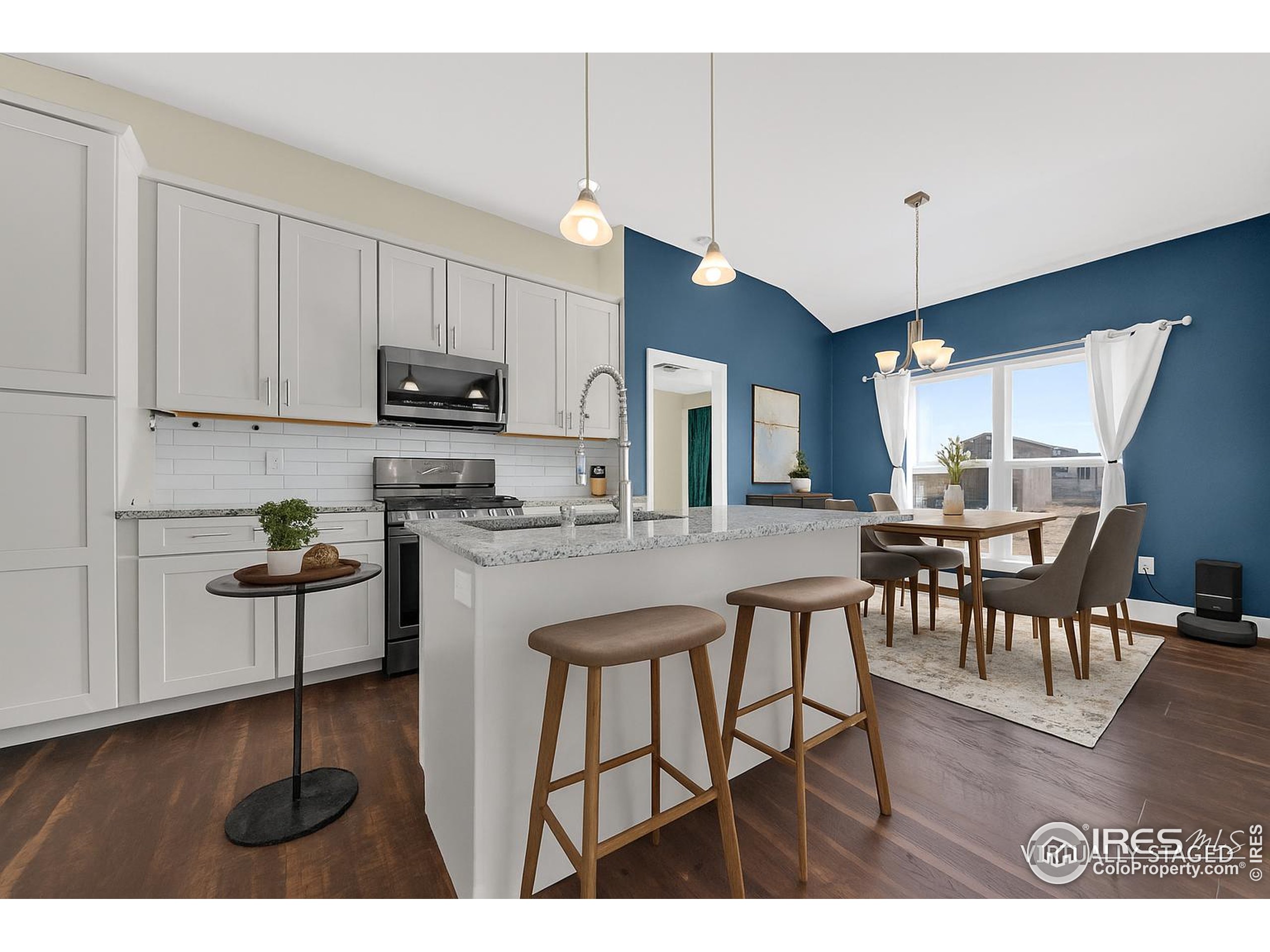7566 County Road Wiggins, CO 80654 - Photo 7 of 23 a kitchen with stainless steel appliances kitchen island granite countertop a table chairs and a white cabinets