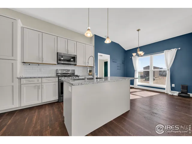 a living room with stainless steel appliances kitchen island granite countertop a stove a sink and a microwave