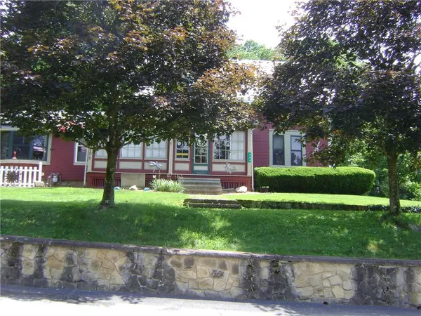 a front view of a house with a garden and trees