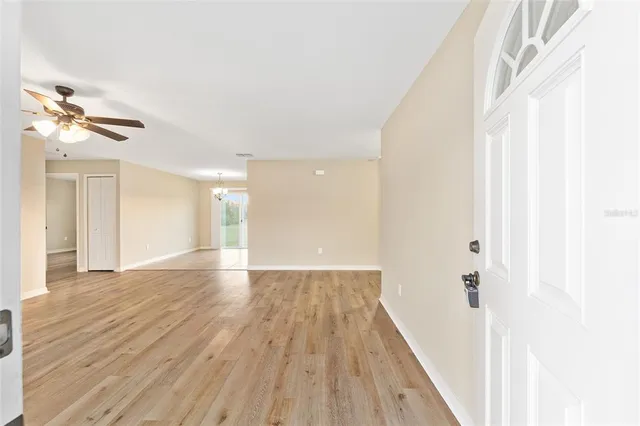 a view of a hallway with wooden floor and a ceiling fan