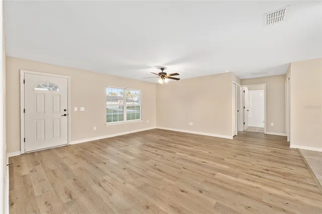 a view of empty room with wooden floor and fan