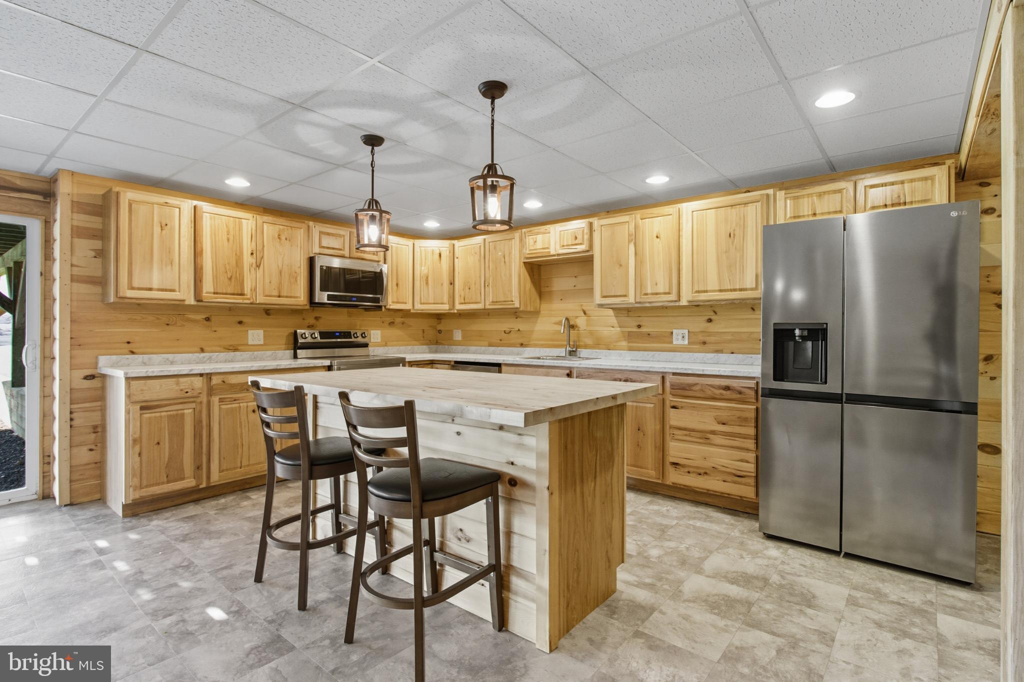 107 Linkin Park Drive Spring Mills, PA 16875 - Photo 50 of 66 a kitchen with kitchen island granite countertop a refrigerator a stove a sink a dining table and chairs with wooden floor