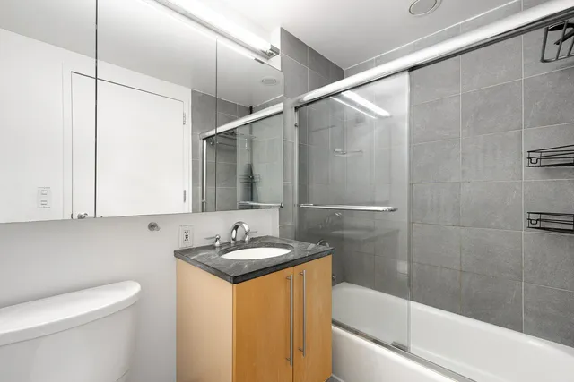 a bathroom with a granite countertop sink a toilet and bathtub