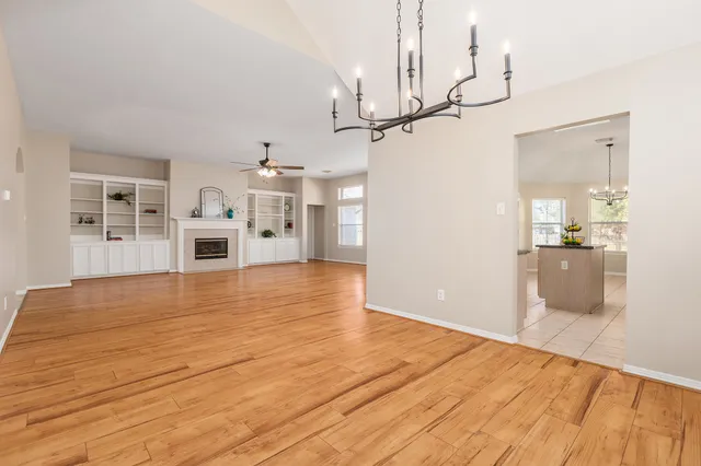 a view of an empty room with a kitchen and wooden floor
