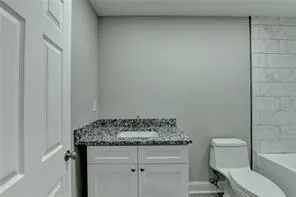 a bathroom with a granite countertop toilet and a sink