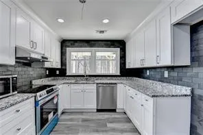 a kitchen with stainless steel appliances granite countertop a stove a sink and a microwave