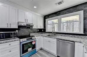 a kitchen with granite countertop cabinets stainless steel appliances a sink and window