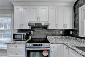 a kitchen with granite countertop white cabinets and appliances