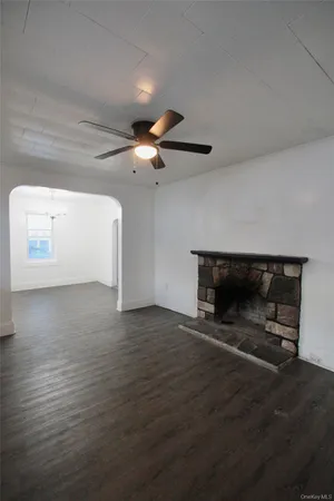 a view of an empty room with wooden floor and a fireplace