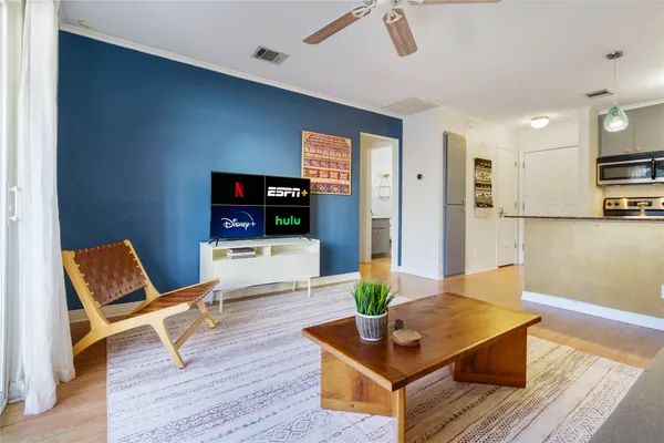 a living room with furniture a flat screen tv and kitchen view