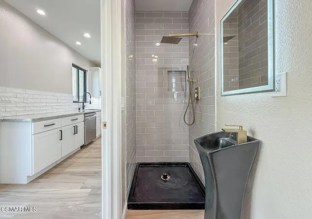 a bathroom with a granite countertop sink a toilet a glass door a shower