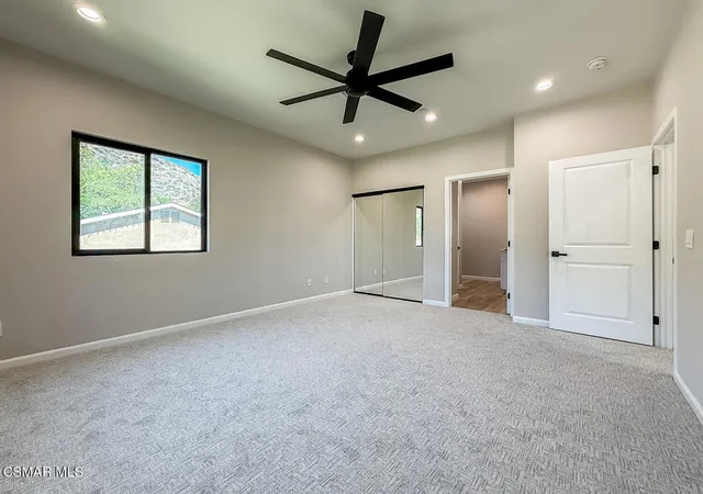 a view of a livingroom with a ceiling fan & windows