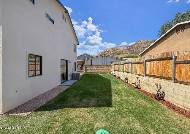 a view of a house with a big yard plants and large tree