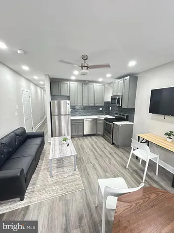 a large white kitchen with lots of counter space dining table and stainless steel appliances