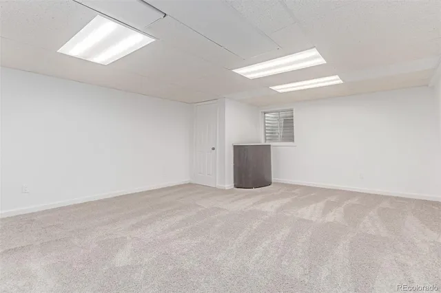 an empty room with windows and refrigerator in it