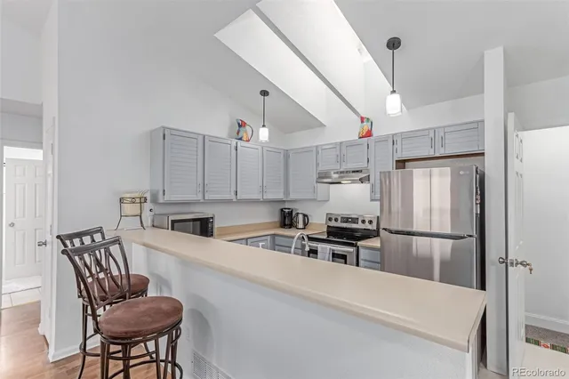 a kitchen with granite countertop a refrigerator a stove a sink dishwasher a dining table and chairs with wooden floor