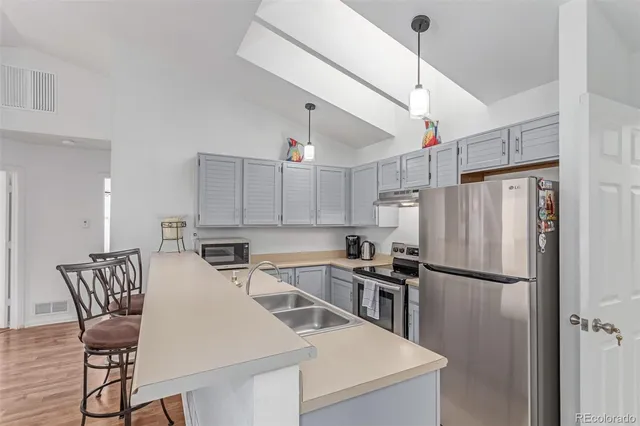 a kitchen with stainless steel appliances a refrigerator a stove a sink and chairs