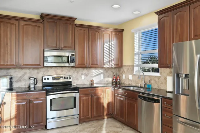 a kitchen with stainless steel appliances granite countertop a stove a sink and a refrigerator