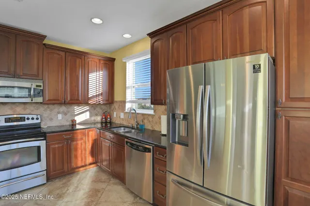 a kitchen with stainless steel appliances granite countertop a refrigerator a sink dishwasher and wooden cabinets