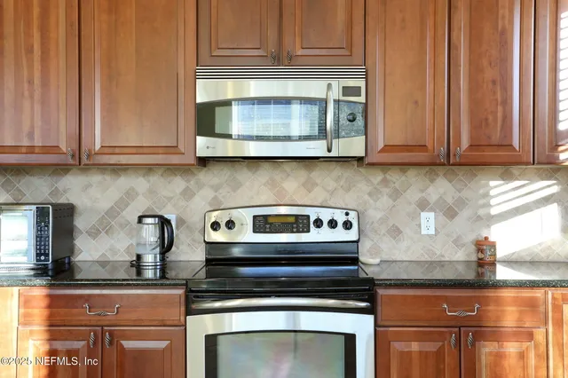 a kitchen with granite countertop wood cabinets and a stove top oven