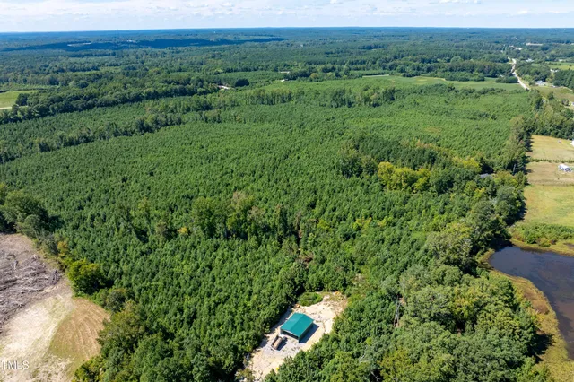 an aerial view of residential house with outdoor space and trees all around