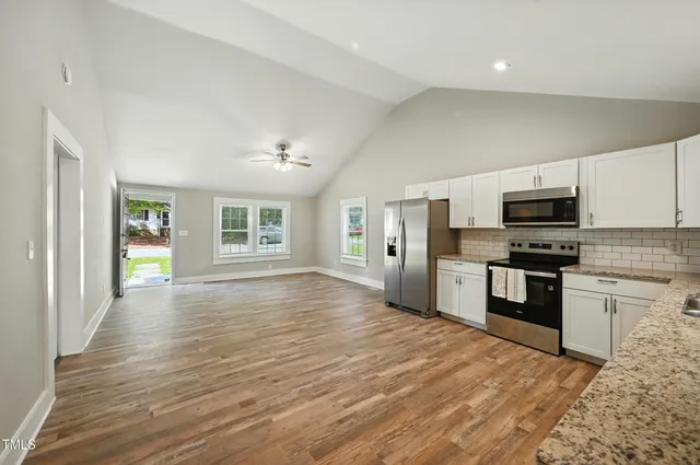 a kitchen with granite countertop a stove top oven and refrigerator