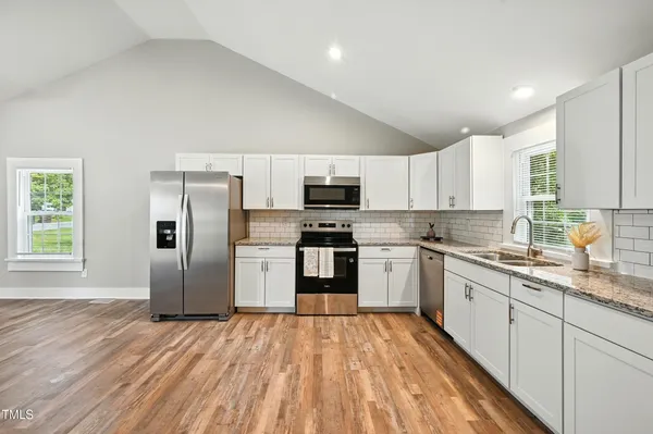 a kitchen with granite countertop a refrigerator stove top oven and sink