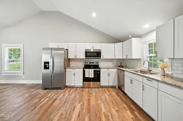 a kitchen with granite countertop a refrigerator stove top oven and sink