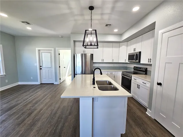 a kitchen with granite countertop a stove a sink dishwasher a refrigerator and a microwave oven with wooden floor