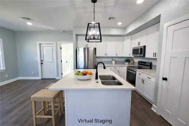 a kitchen with stainless steel appliances granite countertop a sink dishwasher a refrigerator a stove a microwave oven a dining table and chairs with wooden floor