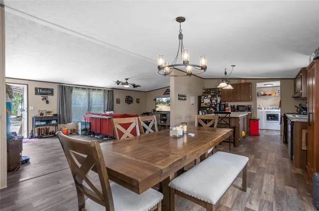 a kitchen with stainless steel appliances granite countertop a stove a refrigerator a kitchen island a dining table and chairs with wooden floor