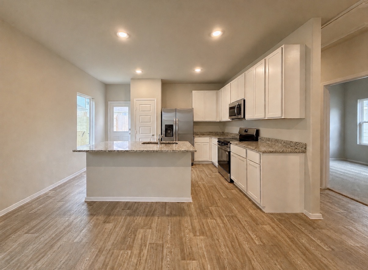 2714 Towy Road Manor, TX 78653 - Photo 7 of 22 A well-appointed kitchen features a central island, granite countertops, and modern stainless steel appliances.