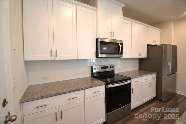 a kitchen with granite countertop white cabinets and stainless steel appliances